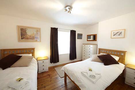 Zwei Einzelbetten im Zweibettzimmer von der Tür von Sorgente aus gesehen, einem kornischen Ferienhaus in Penryn bei Falmouth