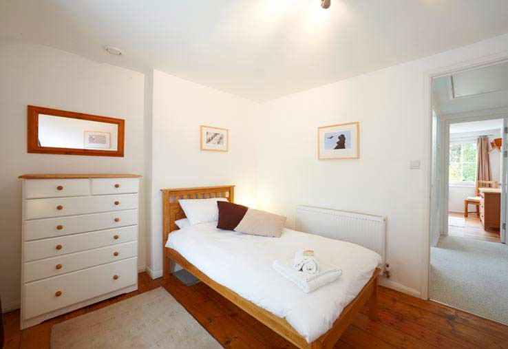 Slaapkamer met 2 aparte bedden en de gang die leidt naar de slaapkamer met tweepersoonsbed - Sorgente Cornish Holiday Cottage in Penryn, nabij Falmouth