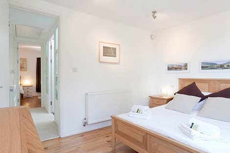 Schlafzimmer mit Doppelbett und Flur mit Zugang zum Schlafzimmer mit zwei Einzelbetten im Ferienhaus Sorgente Cornish bei Falmouth