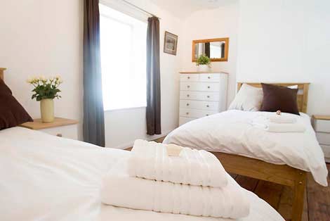 De slaapkamer met twee eenpersoonsbedden en eenpersoonsbedden - Sorgente Cornish Holiday Cottage in Penryn, nabij Falmouth